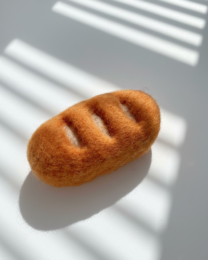 Small handmade baguette wool magnet with soft felted texture and warm tones