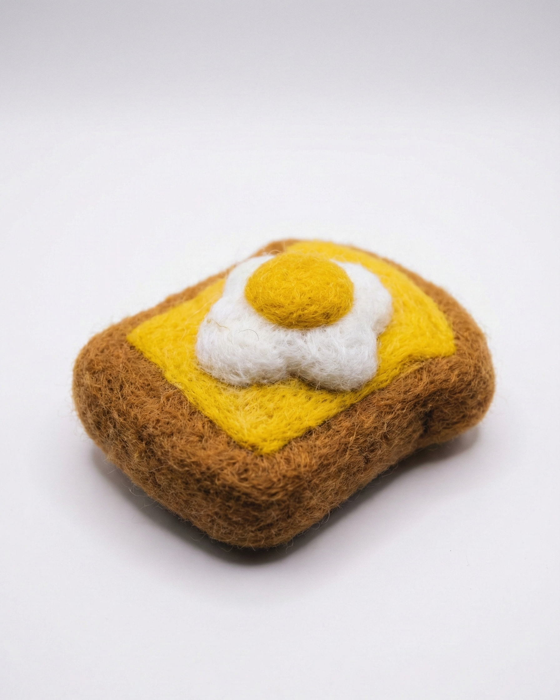 Handmade needle felted egg toast magnet in the white background.