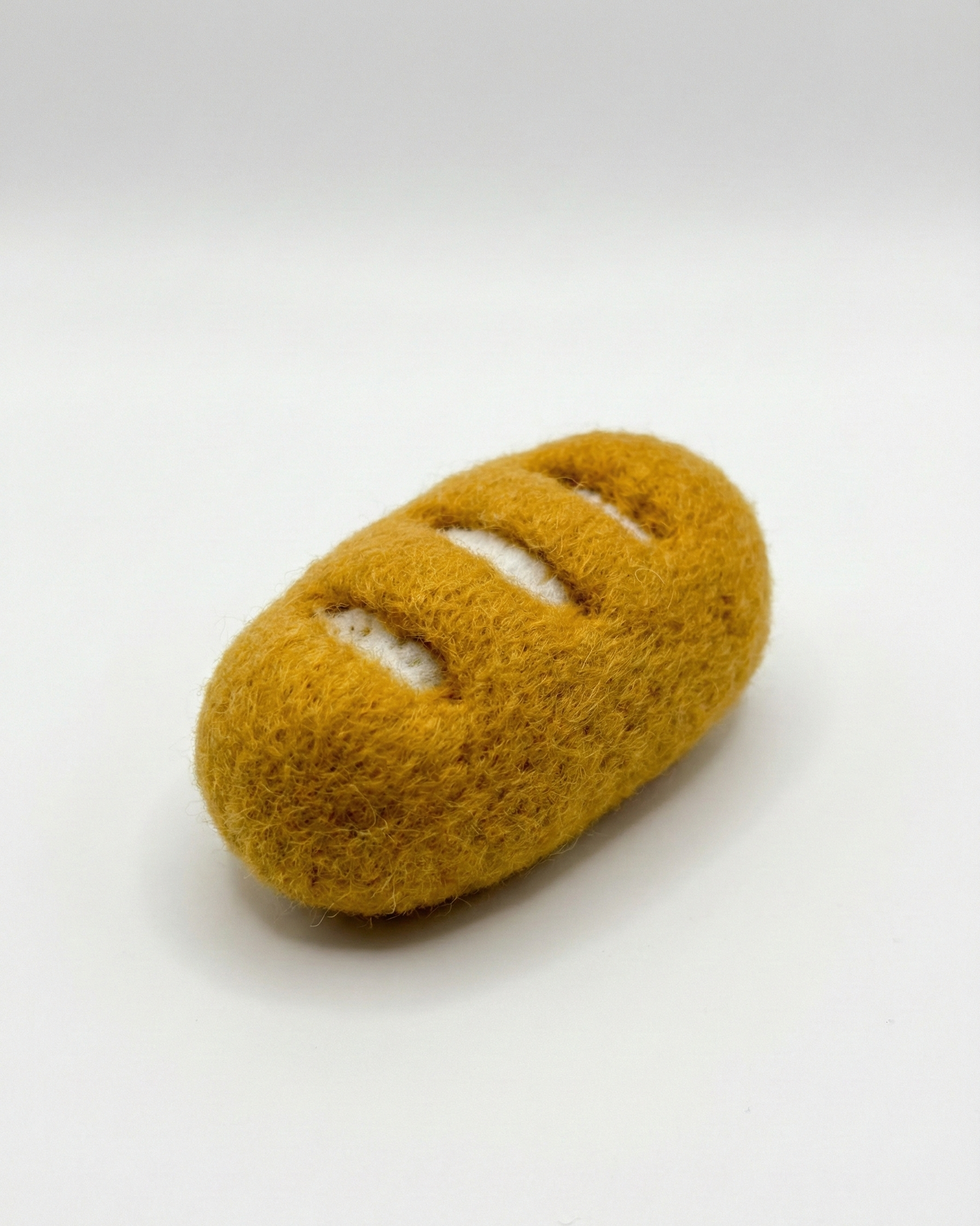 Handmade needle felted Baguette magnet in the white background.