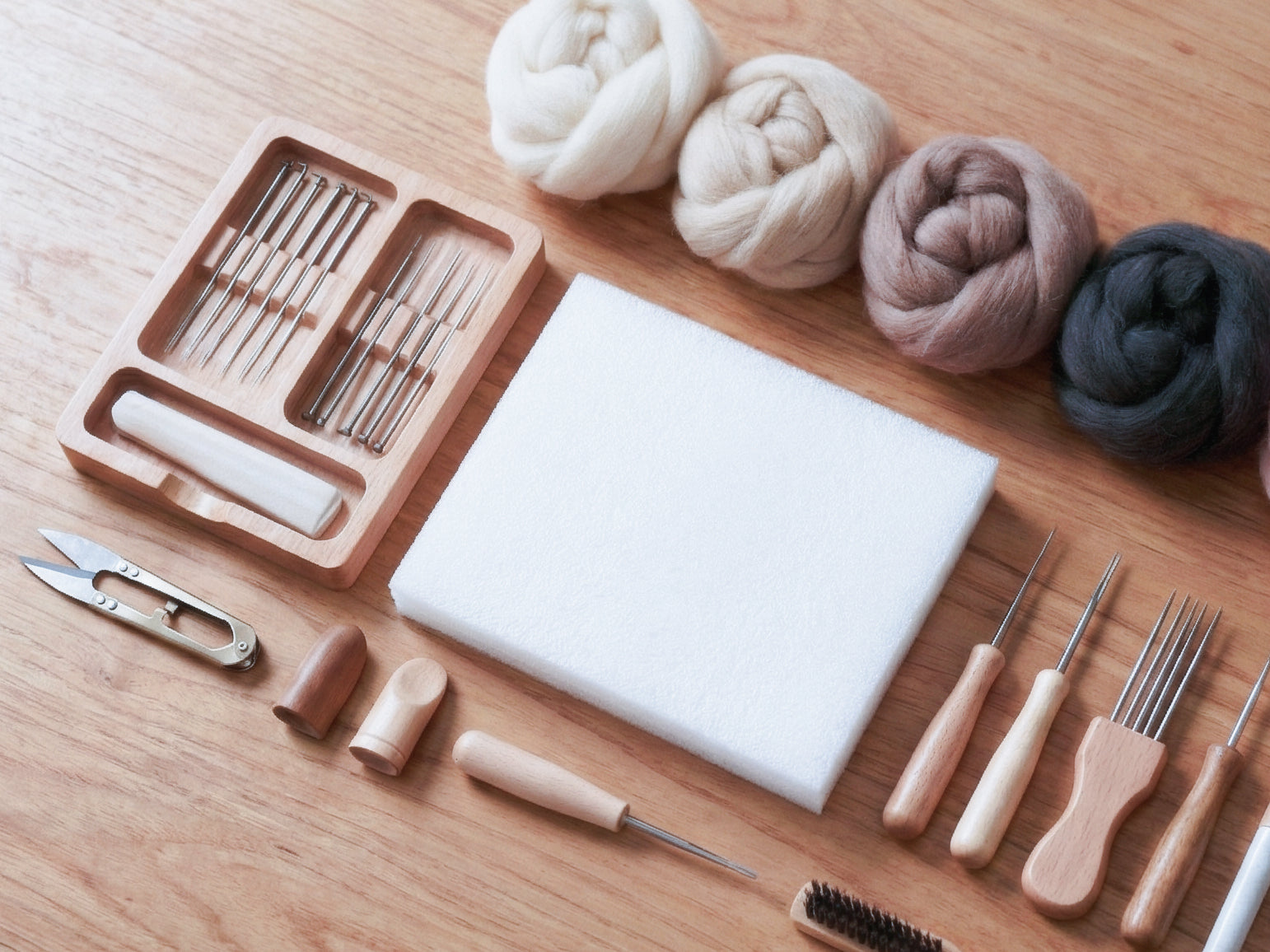 A set of needle felting tools and some wool roving fiber