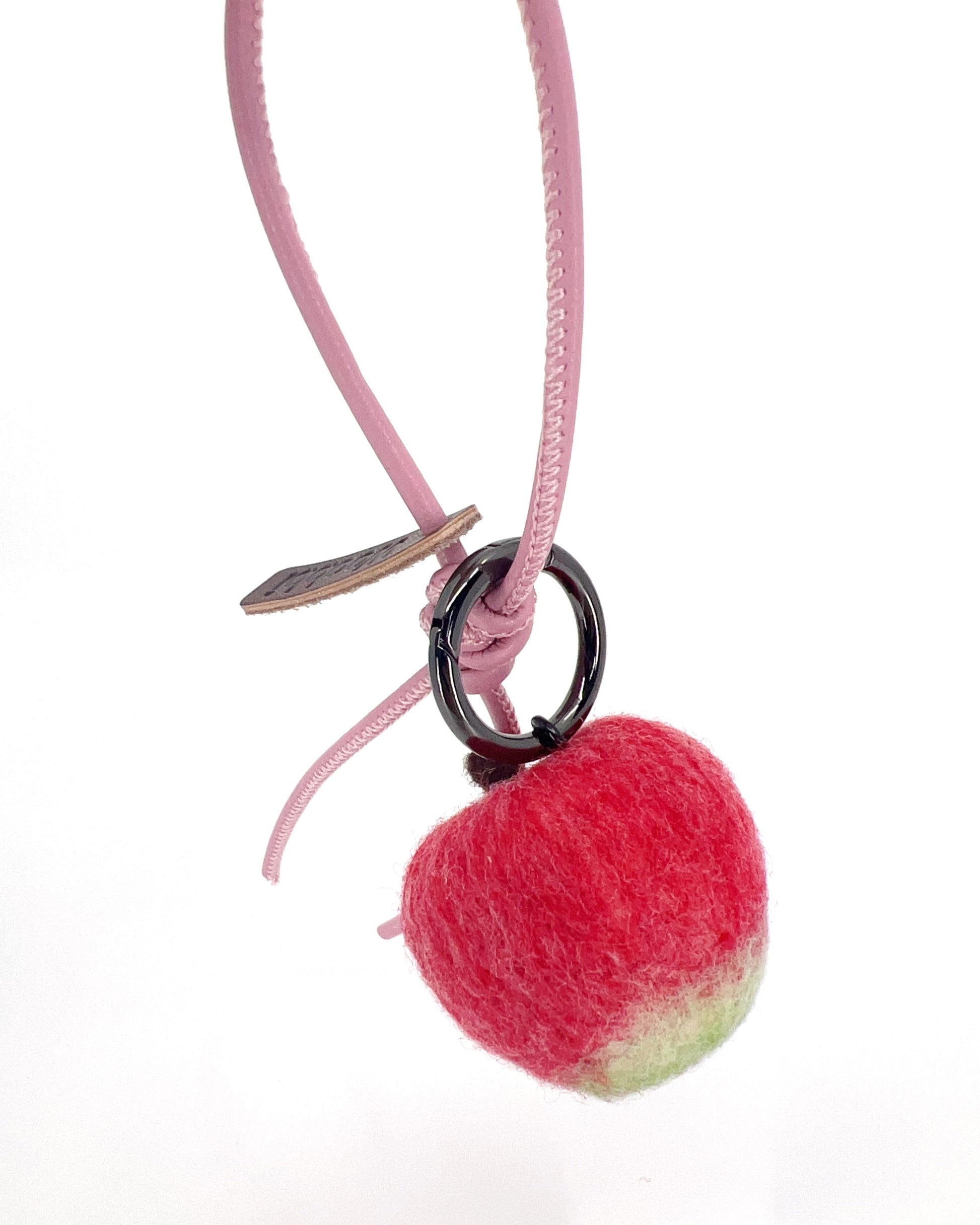 Back view of soft Merino wool apple fruit charm attached to a pastel pink leather loop, showing the textured red-to-green gradient.
