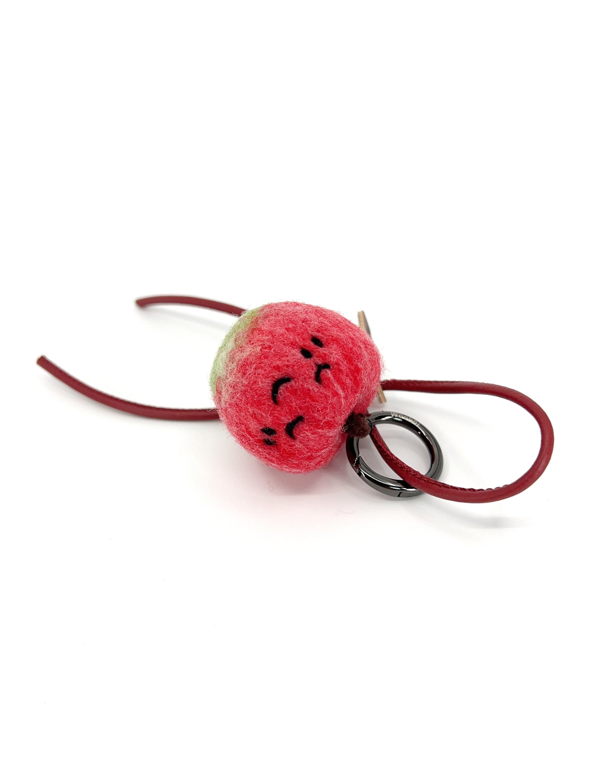 Front view of needle-felted red apple keychain with matching red leather cord, featuring a peaceful sleeping expression and green stem.