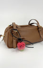 Lifestyle photography of handmade wool apple bag charm clipped onto a brown leather handbag, showing size and styling.