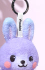Close-up of black metal keychain hardware and white woven logo tag attached to a purple wool bunny charm with gradient blue ears.