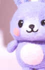 Macro close-up of purple needle-felted bunny face showing soft Merino wool texture, pink cheeks, and hand-stitched smile.
