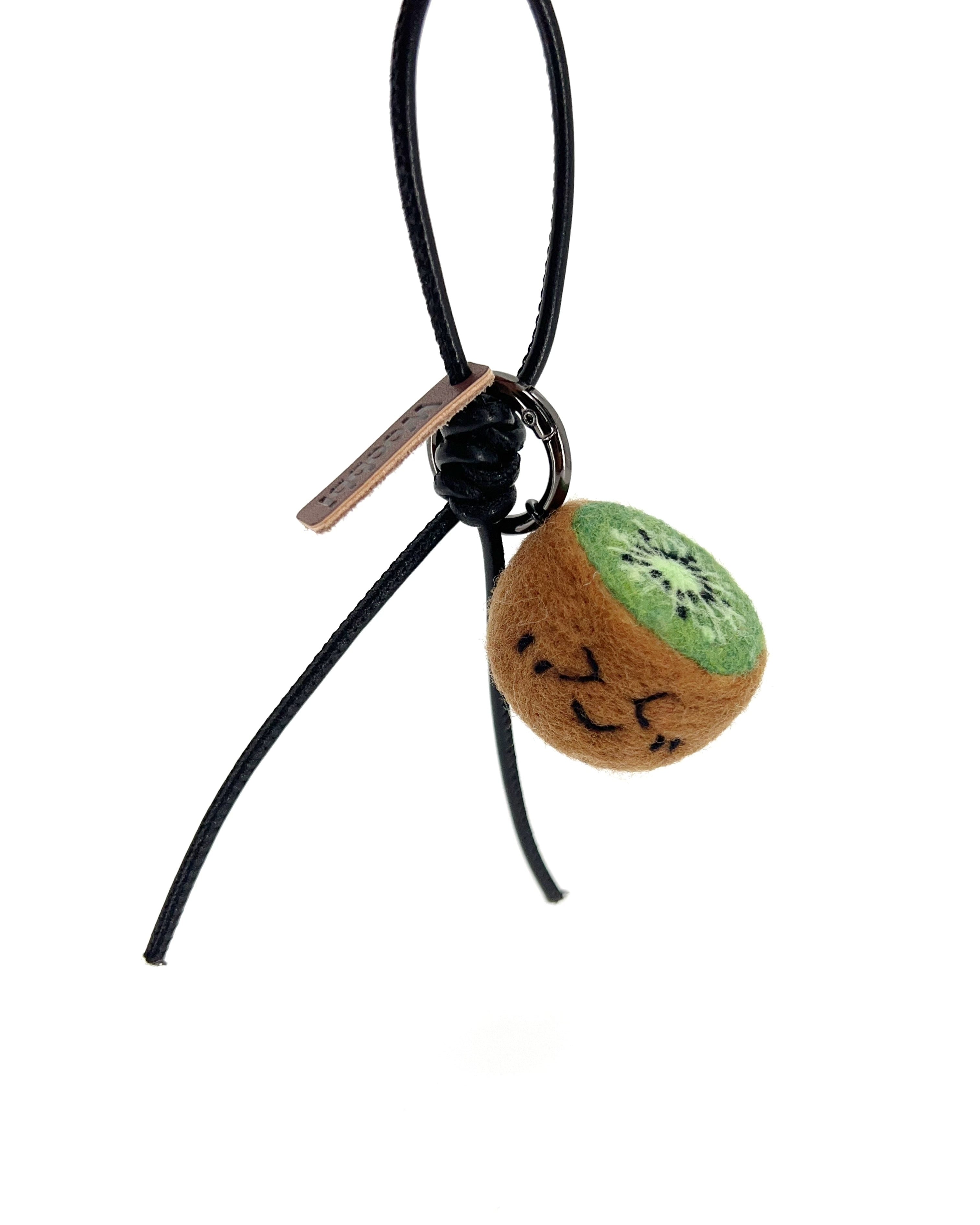 Hanging view of needle-felted wool kiwi bag charm featuring a black leather cord, showing the cute winking face and brown fuzzy texture.