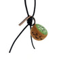 Hanging view of needle-felted wool kiwi bag charm featuring a black leather cord, showing the cute winking face and brown fuzzy texture.