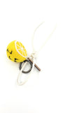 Sustainable citrus bag accessory featuring a yellow needle-felted lemon slice with white leather strap and knot detail.
