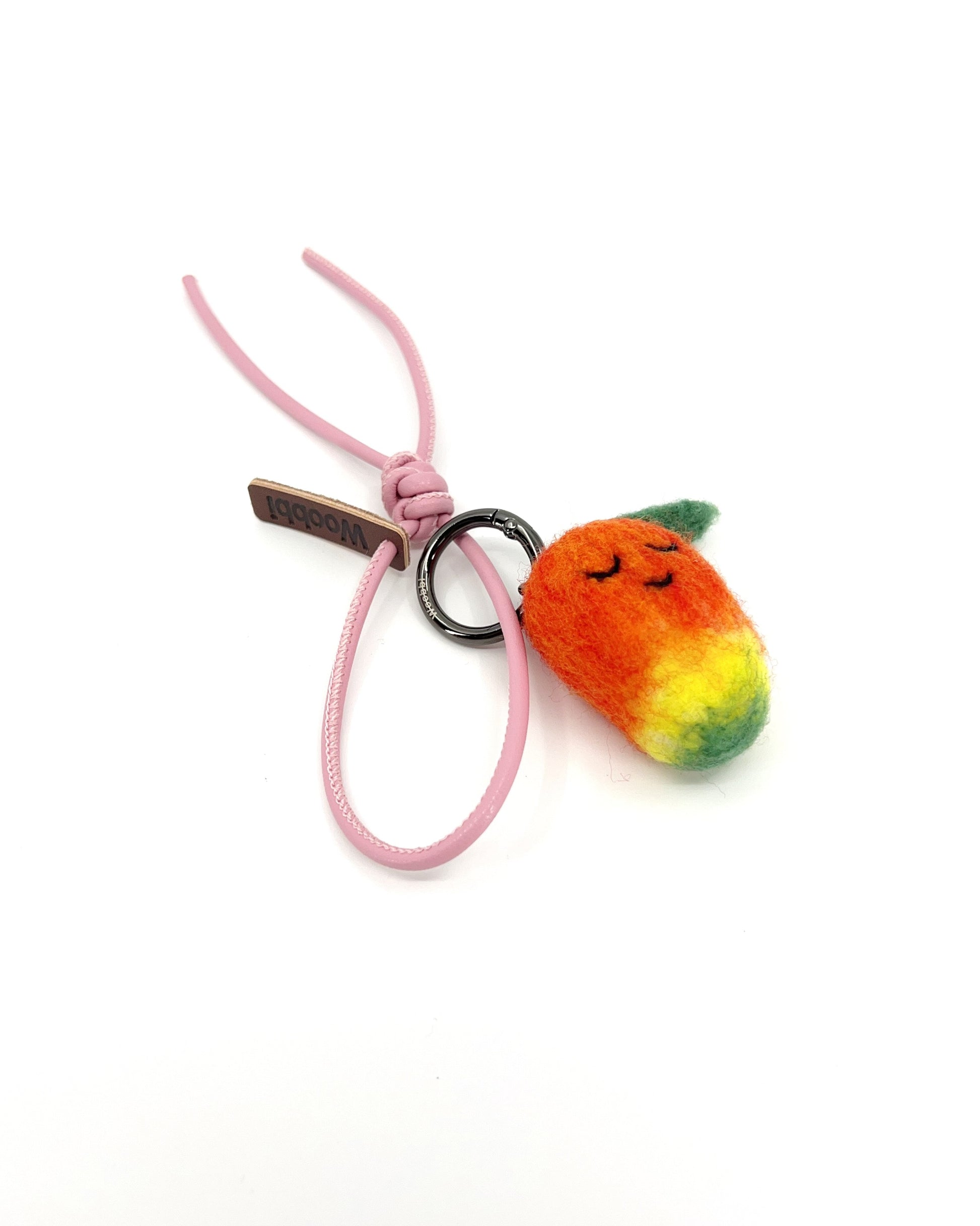 Cute sleeping mango wool accessory with a pastel pink leather strap and black metal hardware, displaying the fuzzy Merino wool texture.