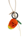Hanging view of needle-felted wool mango bag charm featuring a white leather cord, showing the soft orange-to-yellow gradient and sleeping face.