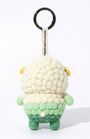 Back view of a handmade Woobbi sheep keychain, made from off-white and green bubbly wool felt. It features a small tag that says 'Designed with ❤️ in Austin' and a round black metal keyring. The sheep has small yellow ears and a tiny white tail. It is set against a plain white background.