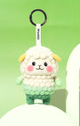 Front view of white and green needle-felted sheep keychain standing on a modern green arch, designed in Austin with sustainable Merino wool.