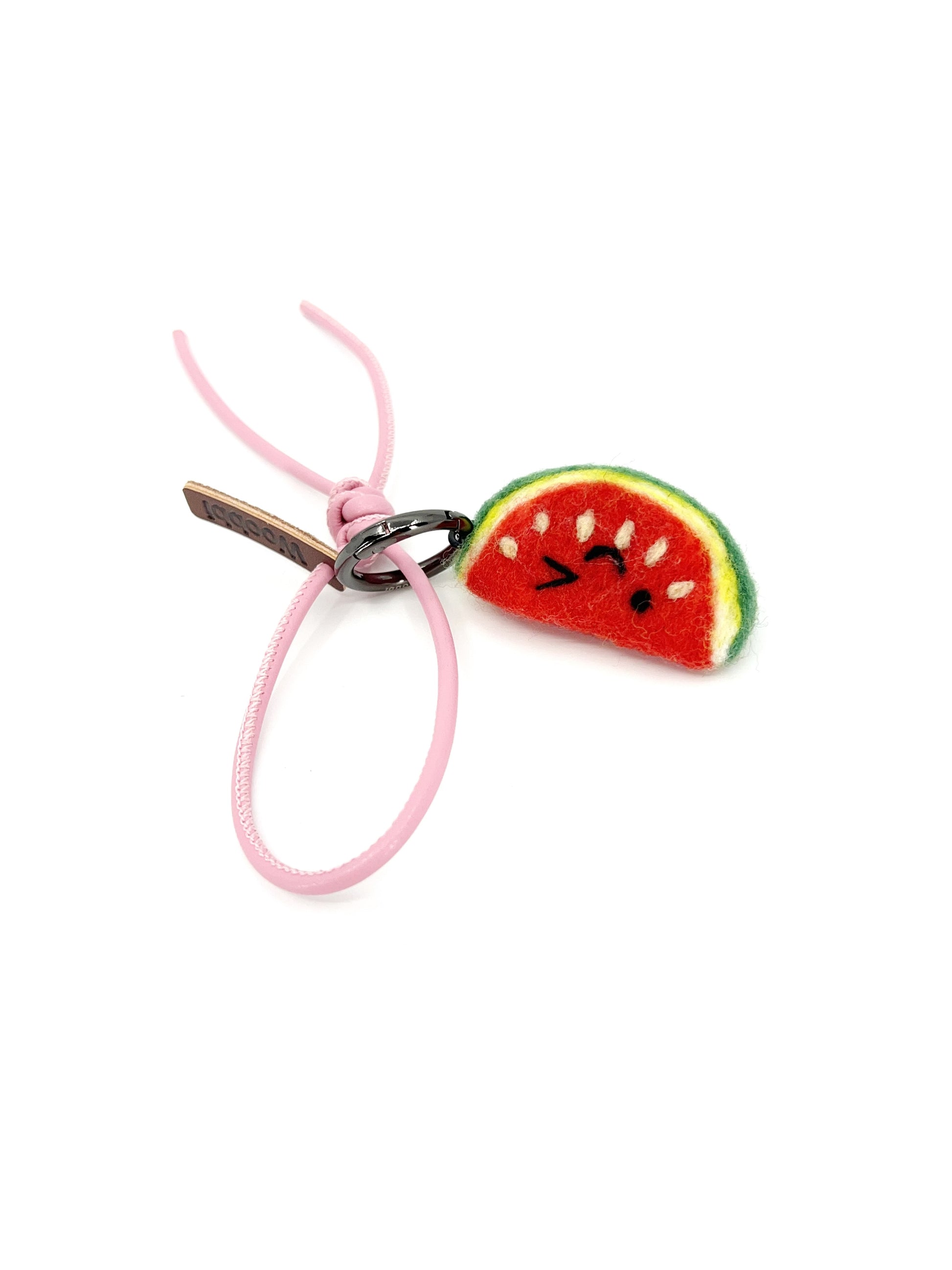 Cute winking watermelon wool bag charm with pastel pink leather strap and logo tag, displayed on a clean white background.