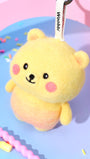 High-angle view of round, chubby wool bear bag charm in yellow and peach, displaying its soft needle-felted shape and secure keychain attachment.