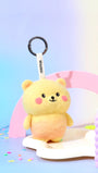 Handcrafted wool bear keychain styled on a pastel party background with colorful candles, showcasing its yellow gradient design and black metal hardware.