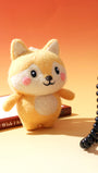 Handcrafted needle-felted yellow fox bag charm standing next to a vintage red rotary phone, styled on a warm orange background.