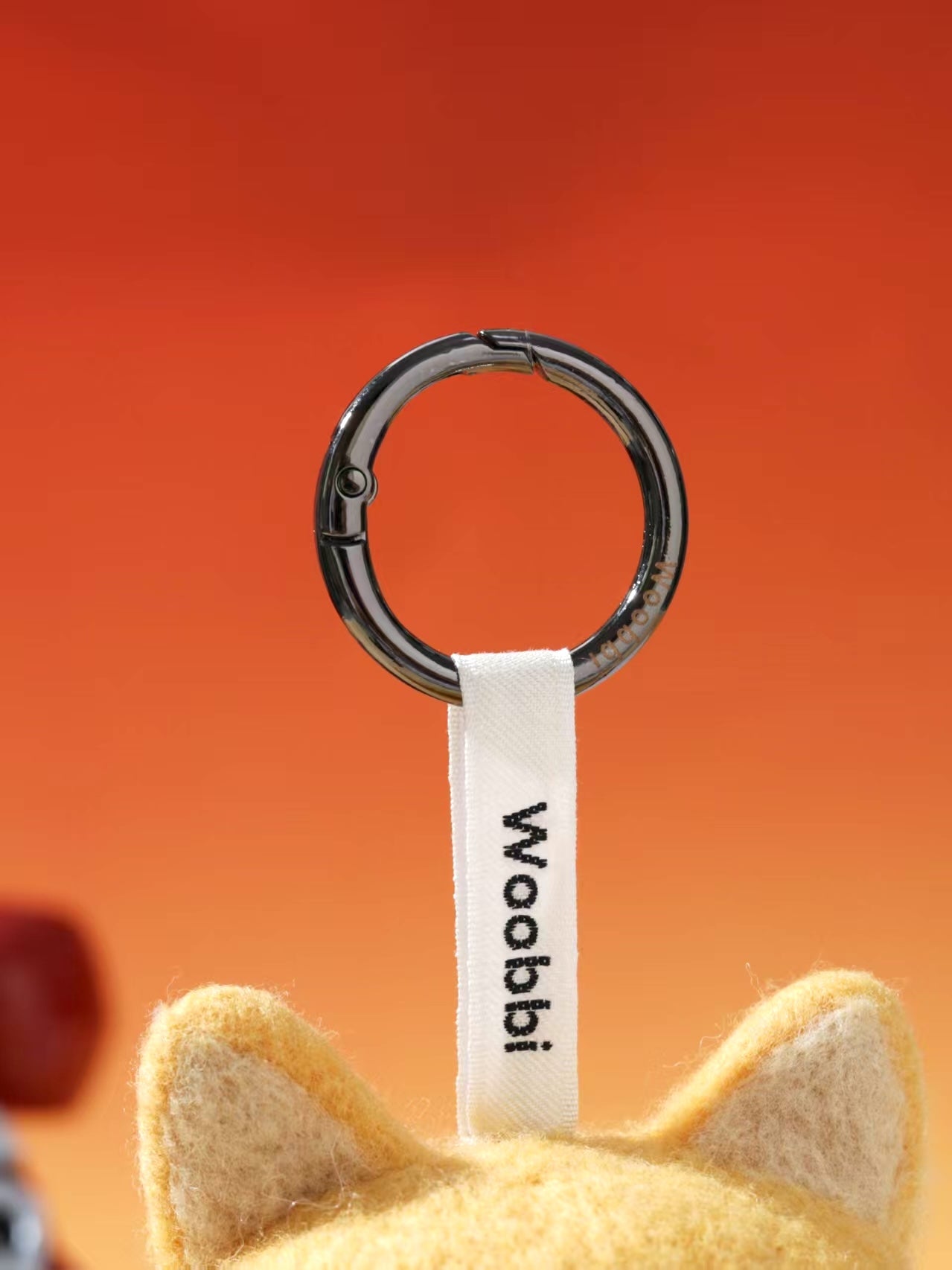 Close-up of durable black metal keychain ring and white woven Woobbi brand tag attached to a wool bag charm.