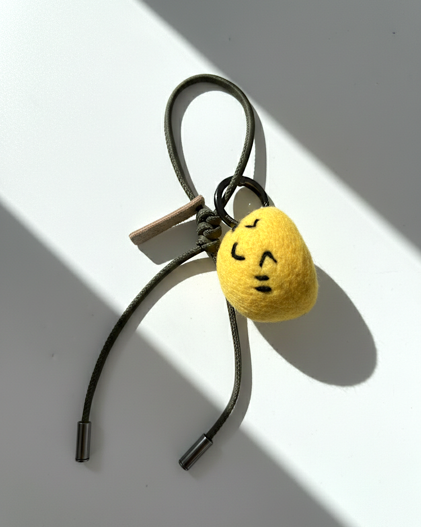 Cute needle-felted lemon smiley face plush charm with olive green cord.