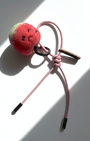 Hanging view of needle-felted wool apple keychain with pink leather cord, featuring a hand-stitched happy smiley face.