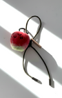 Hanging view of needle-felted wool apple keychain with olive leather cord, featuring a hand-stitched happy smiley face.