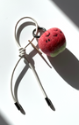 Hanging view of needle-felted wool apple keychain with white leather cord, featuring a hand-stitched happy smiley face.