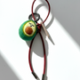 Miniature needle-felted avocado plush charm with dark red burgundy leather cord.