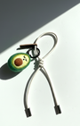 Woobbi felted avocado keychain accessory with off-white cream cord on a white background.