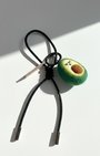 Handcrafted avocado felt charm with black leather cord and polished metal tips.