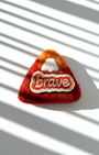 Handmade wool fridge magnet in rust red tones with embroidered Brave patch, needle-felted merino wool