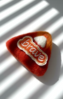 Rust red needle-felted wool magnet with stitched Brave patch, soft rounded shape, handmade fridge decor