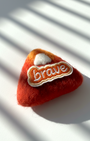 Handmade merino wool fridge magnet featuring Brave embroidery patch, warm red felt texture detail