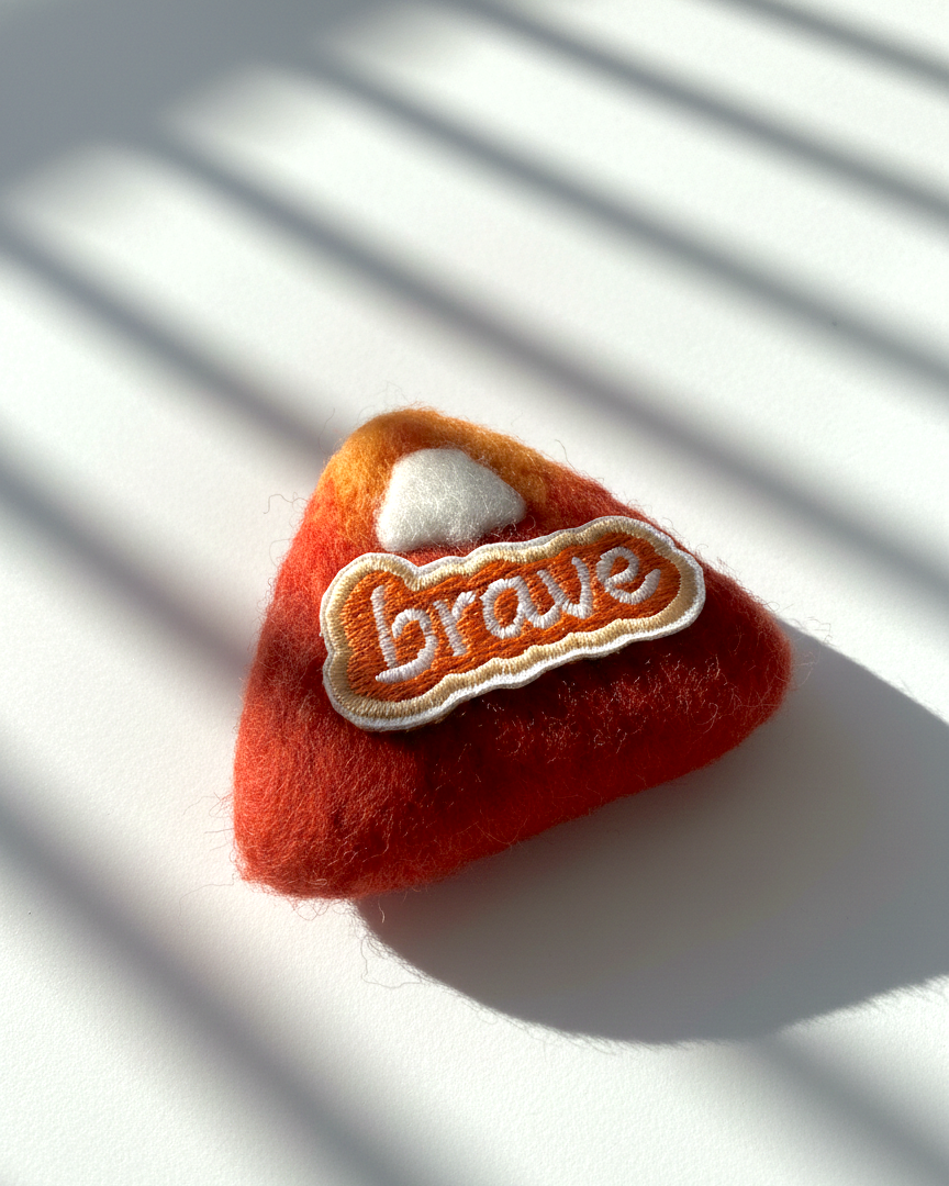 Handmade merino wool fridge magnet featuring Brave embroidery patch, warm red felt texture detail