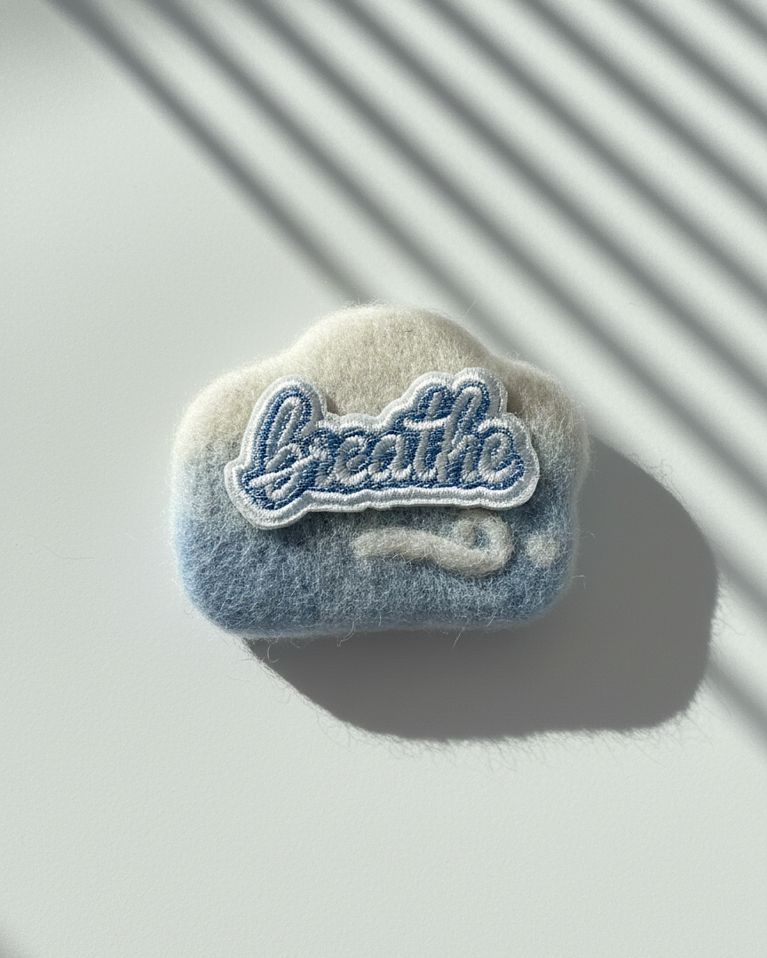 Handmade blue wool magnet with Breathe patch, soft felt texture and rounded form, merino wool fridge decor