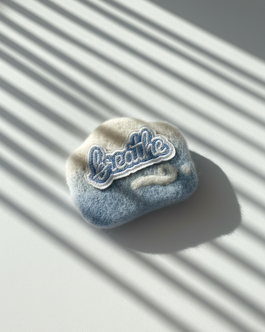 Minimalist wool fridge magnet in calming blue tones with stitched Breathe patch, handcrafted from merino wool