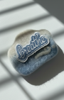 Handmade wool fridge magnet in soft blue and cream tones with embroidered Breathe patch, needle-felted merino wool