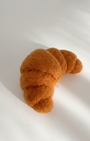 Handmade wool croissant fridge magnet, needle-felted with soft texture and warm golden tones