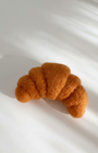 Side view of handmade wool croissant fridge magnet highlighting layered felt folds