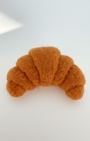Top-down view of needle-felted wool croissant fridge magnet showing curved form