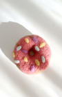 Pink donut-shaped object with colorful sprinkles on a white background