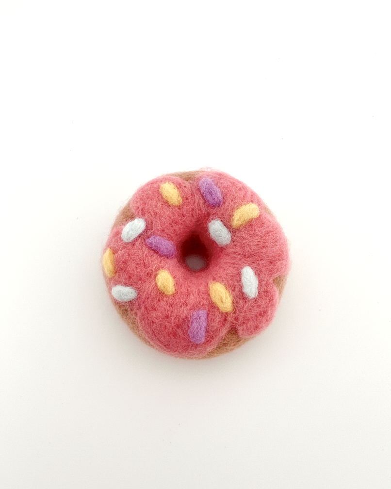 Needle-felted donut magnet made from natural wool, pink frosting with pastel sprinkles