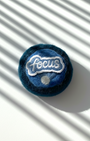 Round handmade wool fridge magnet in layered blue tones with embroidered “Focus” patch, needle-felted from merino wool