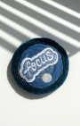 Handmade round wool magnet in deep blue shades featuring a Focus embroidery patch, soft felt texture detail