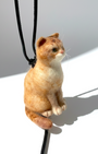 Handmade realistic ginger wool cat sculpture charm in sitting pose, left-side view, needle-felted with lifelike details