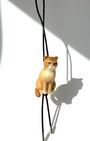 Cat-shaped pendant on a black cord against a white background