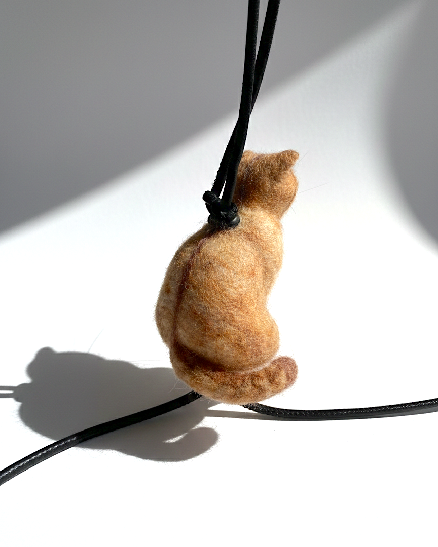 Handmade realistic ginger wool cat sculpture charm in sitting pose, back view, needle-felted with lifelike details, white background