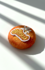 Handcrafted merino wool fridge magnet in warm orange tones featuring Glow embroidery patch