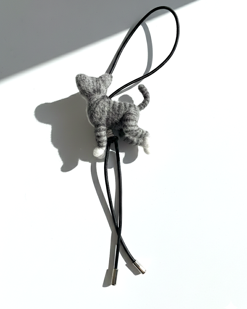 Rear angle of realistic gray tabby wool cat sculpture charm attached to black leather strap