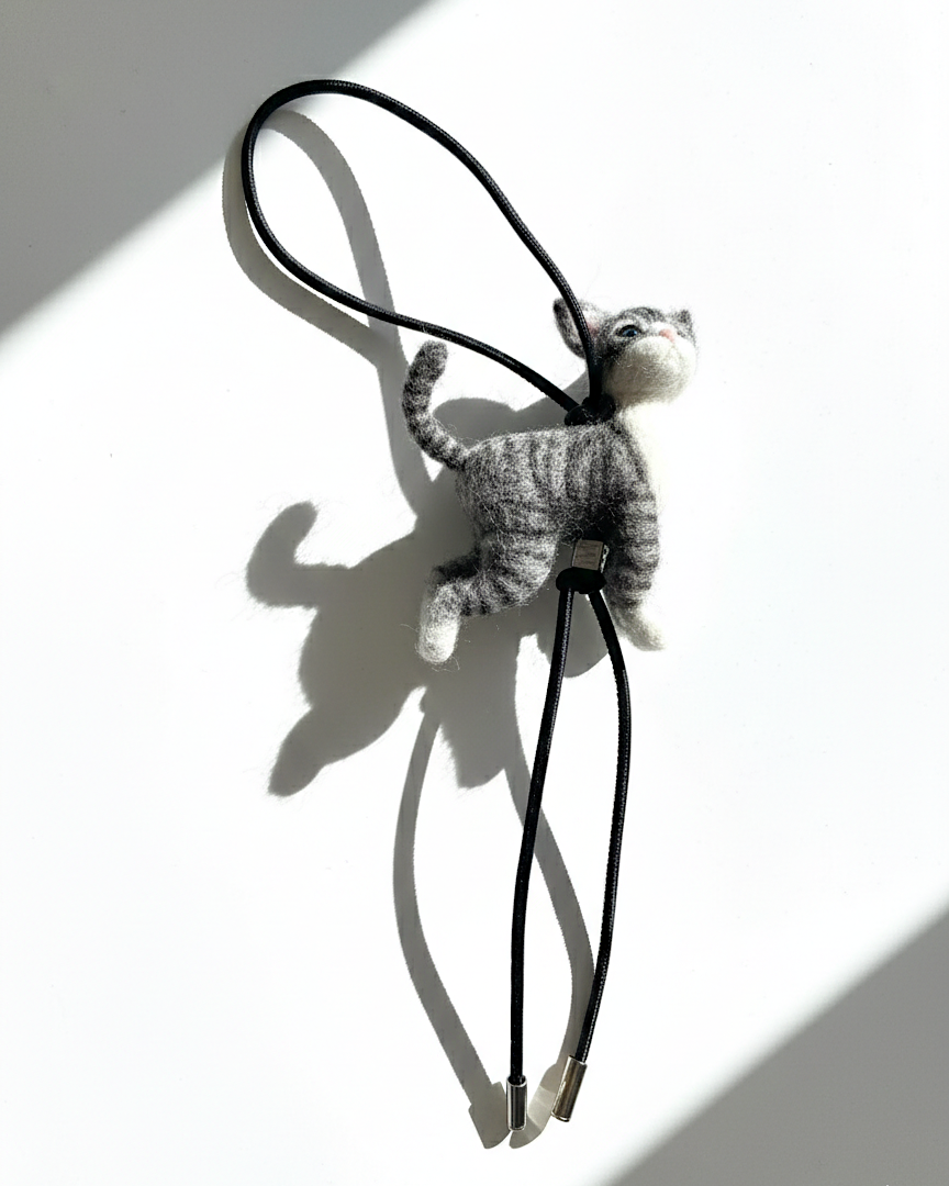 Handmade realistic gray tabby wool cat sculpture charm shown with natural light and sculptural shadow