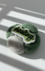 Handcrafted merino wool fridge magnet in green and gray tones with stitched Healing patch