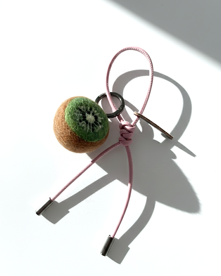 Handmade needle-felted kiwi slice bag charm with a light pink cord and silver hardware.